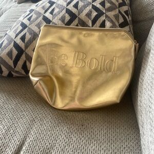 A gold pouch with a zipper slightly used from shoppers drug Mart
